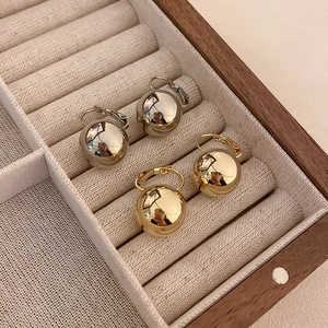 Gros plan détaillé de boucles d'oreilles boules dorées et argentées dans un coffret