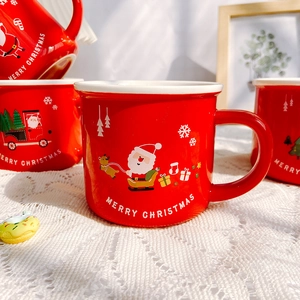 Festive red ceramic Christmas mugs featuring Santa and reindeer designs in a cozy home setting