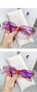 Detail of trendy small cat eye sunglasses with transparent pink frame and purple lenses