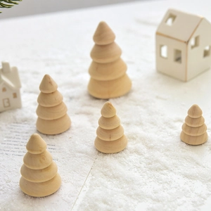 Minimalist wooden Christmas tree set with miniature white houses on snowy background
