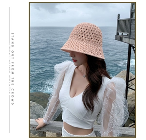 Détail d'un chapeau cloche en maille rose porté par une femme au bord de la mer