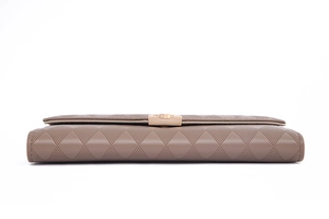 Macro view of light brown PU leather wallet featuring quilted texture and golden hardware