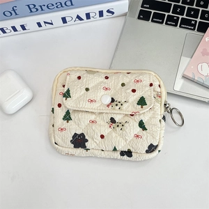 Quilted fabric pouch with Christmas patterns and metal keyring on a desk setup