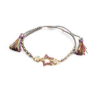 Détail d'un pendentif étoile en cristal rose sur un bracelet tissé aux perles dorées