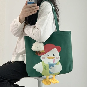 Close-up of dark green canvas tote bag featuring a cute cartoon duck and 3D plush duck feet