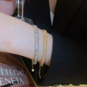 Detail of silver and gold layered diamond chain bracelets worn for a luxury social look