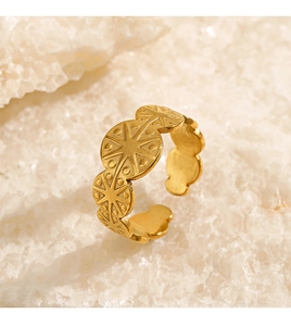 Macro detail of golden starburst engraved circular discs on an adjustable open ring