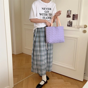 Quilted heart handbag in purple with pink handles shown in a lifestyle indoor setting