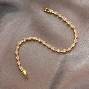 Detailansicht eines Gold-Tennisarmbands mit Marquise-Zirkonia auf grauer Seide