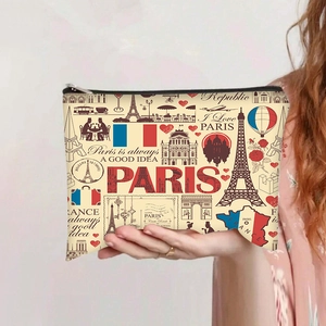 Detailed view of canvas Paris-themed cosmetic bag held by hand with Eiffel Tower print