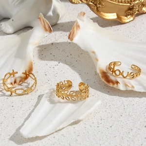 Three gold stainless steel open rings with cross, leaf and love designs on shell