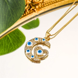 Détail du pendentif lune et cœur doré avec charmes mauvais œil et zircons blancs brillants