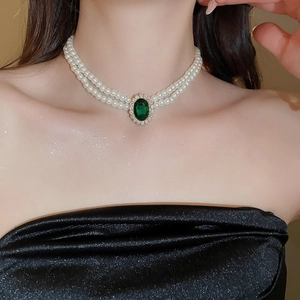 Detail of double-layer pearl choker with oval emerald pendant and gold setting