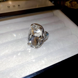 Macro view of a large rectangular crystal ring with ornate silver floral patterns