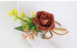 Macro view of handmade deep red artificial rose boutonniere with green leaves and berries