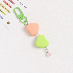 Detail of sweet heart charms in orange and green with pink bead on metal keychain