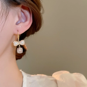 Close-up of elegant bow earrings with pearls and crystals on a model's ear