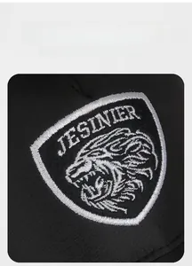 Close-up of embroidered Jesinier lion head shield patch on a black mesh baseball cap