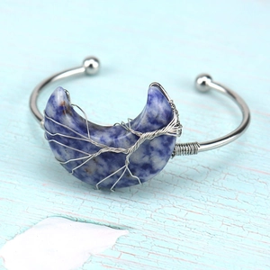 Macro detail of handmade silver wire wrapped tree of life on natural moon stone bracelet