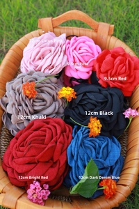 Detailed fabric rose hair claws in various sizes and colors displayed on a woven basket