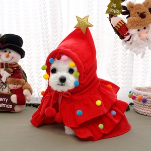 Detail of red plush Christmas pet cape with colorful pom-poms and gold star ornaments