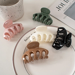 Flat lay of five glossy hair claws in green, pink, cream, black, and brown colors