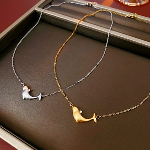 Detail of gold and silver whale tail pendants with matte finish and small zircon stones
