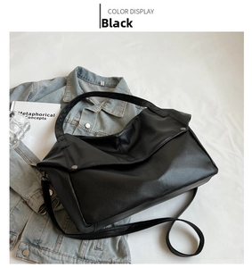 Detailed top view of black lychee grain leather tote bag on denim jacket and books