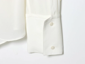 Detail of white long sleeve shirt cuff with high-quality resin buttons and silky texture