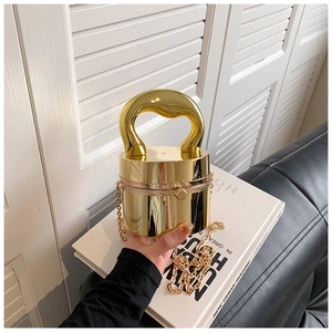 Detailed view of shiny gold cylindrical acrylic handbag with large curved handle and chain
