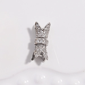 Detailed view of silver bow-shaped jewelry clasp paved with white zircon stones