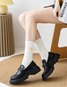 Close-up of white ribbed socks with planet embroidery paired with black platform loafers