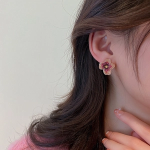 Close-up of a model wearing retro floral stud earrings with pink beads and gold metal