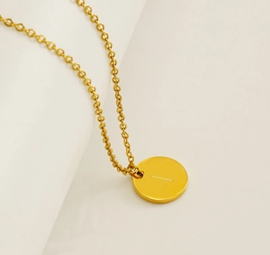 Vue macro d'un collier en acier inoxydable doré avec pendentif rond gravé de la lettre I
