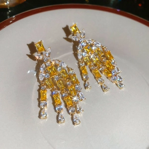 Detailed view of luxury tassel earrings with yellow and white stones in a porcelain dish