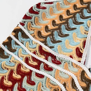 Macro d'un motif de vagues en tricot coloré avec détails au crochet sur robe bohème