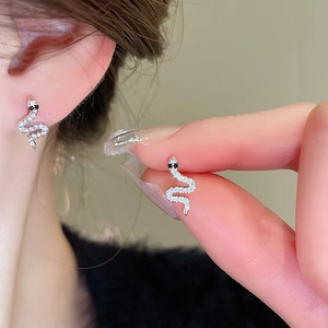 Detailed macro view and model shot of crystal-encrusted silver snake stud earrings