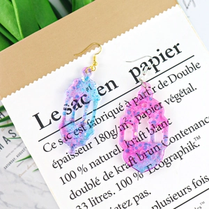 Detailed view of lantern-shaped resin earrings with blue and pink glitter gradients