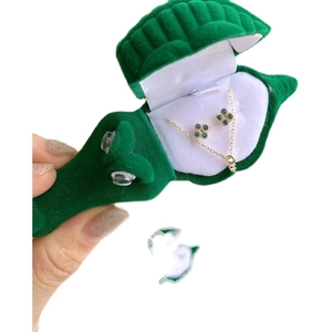 Coffret à bijoux en velours crocodile vert avec collier et boucles d'oreilles trèfle bleu.