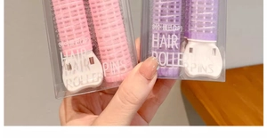 Close-up of pink and purple hair roller pins in retail packaging for root volume