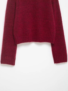 Close-up of ribbed hem and cuffs on a plush burgundy knit sweater in high detail