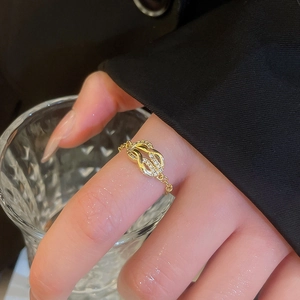 Macro shot of French horseshoe buckle chain ring with zircons in gold finish on finger
