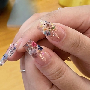 Floral press-on nails with colorful dried flowers and gold leaf for elegant manicures