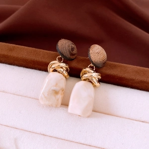 Macro detail of vintage geometric wood and marble resin drop earrings with gold twist knot