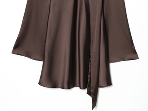 Détail d'une robe en satin marron avec texture de soie lisse et cordon de serrage assorti