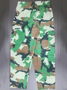 Detail of cargo pants showing camouflage pattern and elastic waistband on wood floor