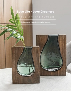 Detail of tear-shaped green glass vases held in minimalist rectangular wooden frames