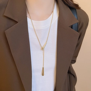 Detailed view of minimalist gold Y-necklace with teardrop pendant worn on a model