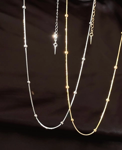 Detailed close-up of gold and silver snake chain necklaces with metallic beads