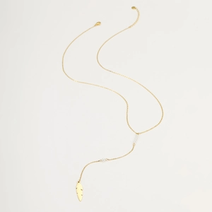 Detailed view of long gold necklace featuring white pearls and a feather pendant